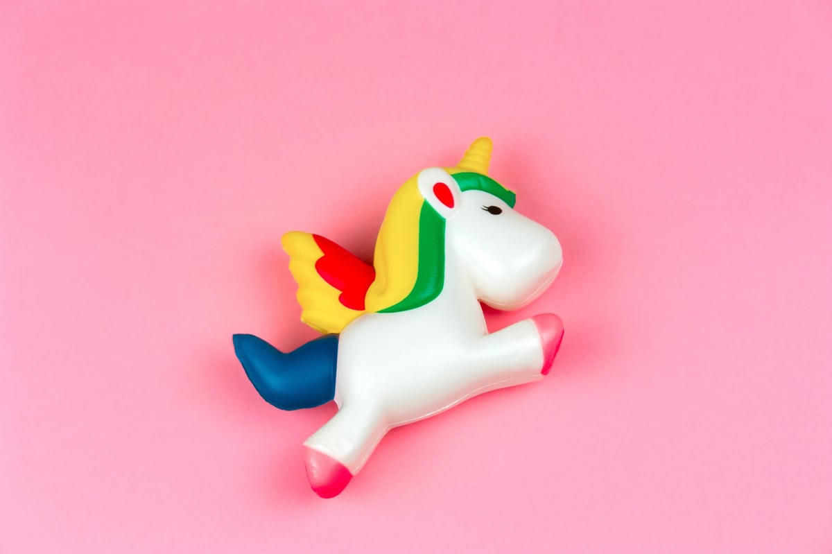 Top view of a squishy unicorn toy on a pastel pink background