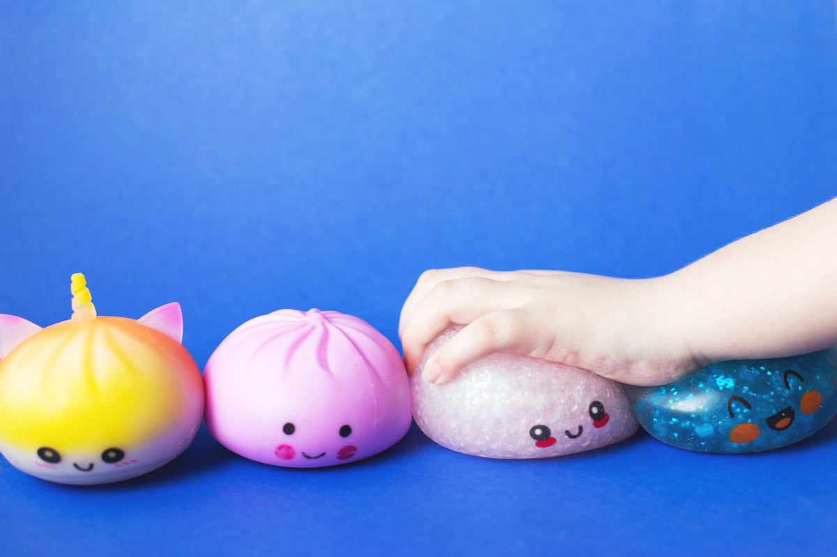 Child's hand squeezing cute squishy toys for sensory play